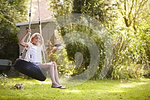 Portrait Of Young Girl Playing On Tire Swing In Garden