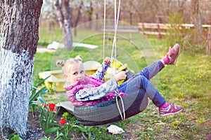 Portrait of young girl playing on tire swing in garden