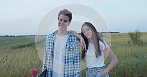 Portrait of young girl poses, leans on male shoulder and they smile at camera