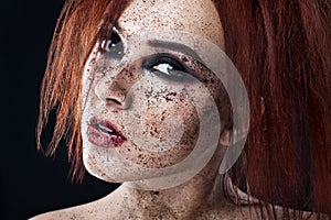 Portrait of young girl with red hair and ground coffee on the face. Photo with art makeup. Mature woman making cosmetic mask. Face