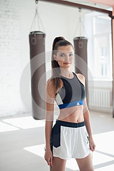 Portrait of a young girl with a rope in the hall, boxing bags in the background