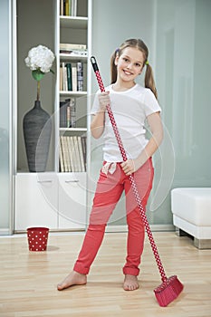 Portrait of a young girl sweeping floor with broom