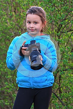 Portrait of young girl taking photography classes at countryside holding camera in hands