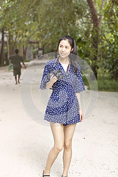 Portrait of young girl traveler holding camera walking on the beach in summer time.