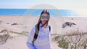 Portrait of young girl traveller with backpack on sea sand beach on vacation.