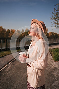 Portrait of a young girl wearing a hat and having coffee