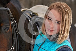 Portrait of a young girl with white hair next to a brown horse. The girl holds the horse. Close-up