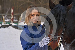 Portrait of a young girl with white hair next to a brown horse. The girl holds the horse and smiles. Close-up