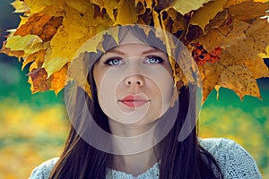 Portrait of a young girl with a wreath of leaves on her head in an autumn park