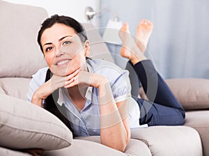 portrait of young glad woman lying on sofa