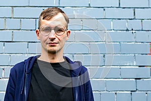 Portrait of young goodlooking man against grey brickwall.