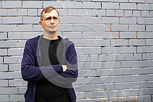 Portrait of young goodlooking man against grey brickwall.