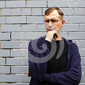 Portrait of young goodlooking man against grey brickwall.