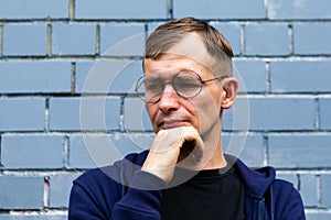 Portrait of young goodlooking man against grey brickwall.