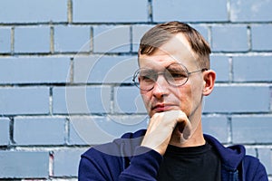 Portrait of young goodlooking man against grey brickwall.