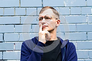 Portrait of young goodlooking man against grey brickwall.