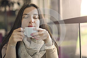 Portrait of young gorgeous female drinking cup of coffee and enjoying her leisure time alone