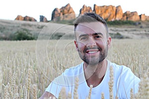 Portrait of a young gorgeous natural man sitting in a wheat field
