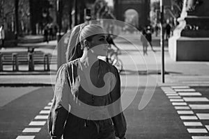 Portrait of young gorgeous woman confidently crossing the road along street. Black and white