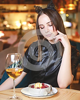 Portrait of young gorgeous woman drinking champagne in a glass and looking with smile, eating ice cream fruit dessert.