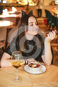 Portrait of young gorgeous woman drinking champagne in a glass and looking with smile, eating ice cream fruit dessert.