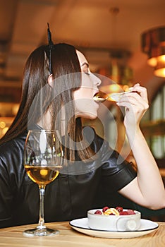 Portrait of young gorgeous woman drinking champagne in a glass and looking with smile, eating ice cream fruit dessert.