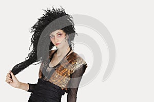 Portrait of young Goth woman with teased hair over gray background