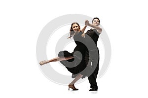 Portrait of young graceful dancers wearing black stage outfits dancing ballroom dance isolated on white background