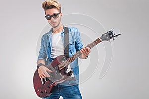Portrait of young guitarist playing guitar in studio