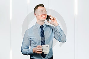 Portrait of young guy businessman dressed in blue shirt and tie, talking on the mobile phone