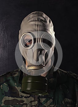 Portrait of a young guy in camouflage with an army gas mask on his head