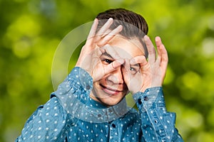 Portrait young guy dressed blue shirt. man open his eyes wide hands fingers smiling. Man on green bokeh background