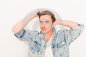 Portrait of young guy in jeans jacket combing hair