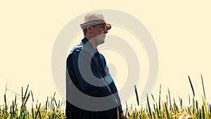 Portrait of a young guy man in a working uniform and a straw hat in the middle of a field around wheat and hay, running around i