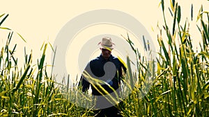 Portrait of a young guy man in a working uniform and a straw hat in the middle of a field around wheat and hay, running around i