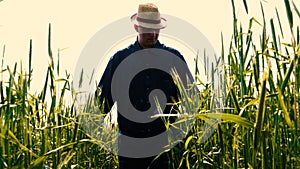 Portrait of a young guy man in a working uniform and a straw hat in the middle of a field around wheat and hay, running around i