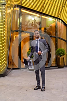 Portrait of young handsome African businessman outdoors