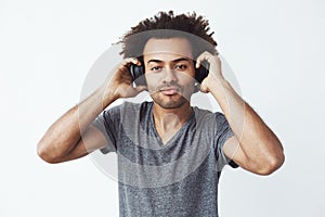 Portrait of young handsome african man listening to music over white background.