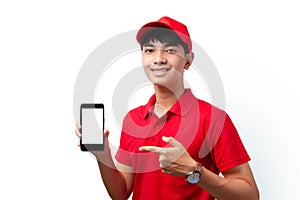 Portrait of young handsome Asian delivery man holding smartphone standing on white background