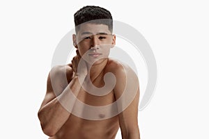 Portrait of young, handsome, asian man with clear spotless face posing shirtless against white studio background