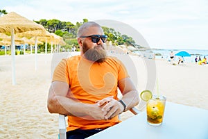 Portrait of young handsome bearded man sitting in a beach cafe or chiringuito photo