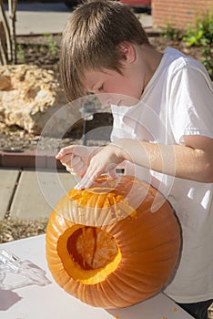 Portrait of a young handsome boy outside carving pumpkins