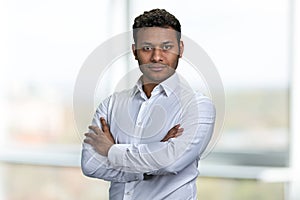 Portrait of young handsome businessman with arms crossed posing on blurred background.