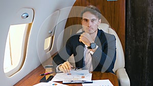 Portrait of young handsome chief banker director businessman flying in airplane in business class. Successful business