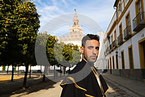 Portrait of young and handsome gipsy man, dressed in black and red shoes and with a black and yellow bullfighter`s cape over his