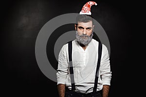 Portrait of young handsome man with beard in snow over black background.