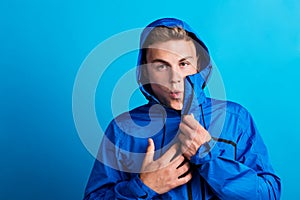 Portrait of a young man with blue anorak in a studio, feeling cold. Copy space. photo