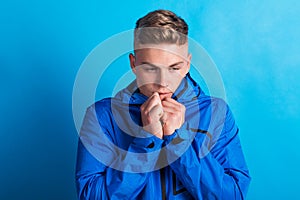 Portrait of a young man with blue anorak in a studio, feeling cold. Copy space. photo