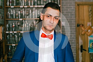 Portrait of young handsome man in blue suit with red bow tie.