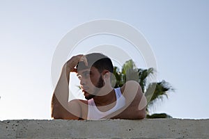 Portrait of a young handsome man dressed in jeans and white t-shirt. The young man is leaning on railing and makes different